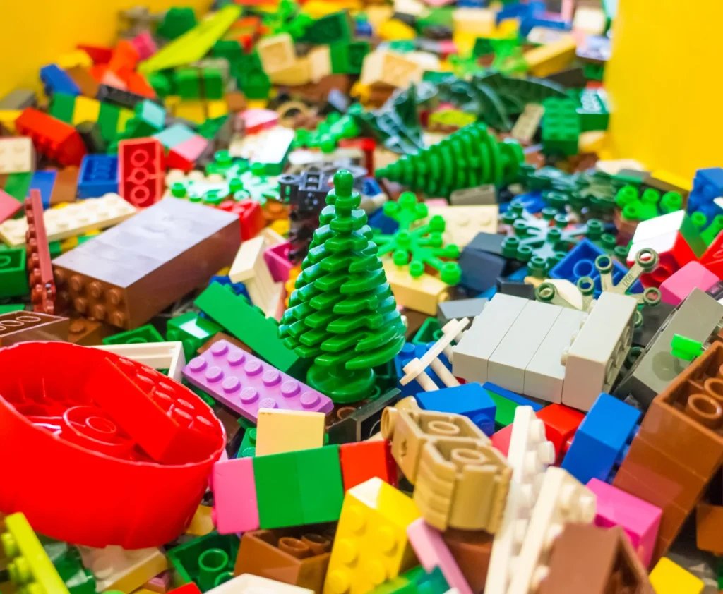 Assorted colorful LEGO bricks, including a green LEGO tree piece, in a bulk collection