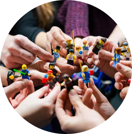 Group of hands holding different LEGO mini-figures, showing a variety of characters in a collaborative and playful setting.