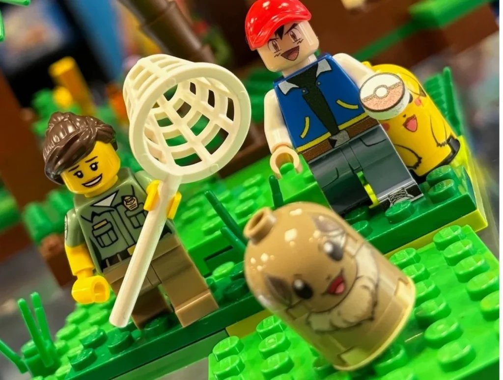 LEGO mini-figures inspired by Pokémon, featuring a character with a net, another with a red cap, and Pokémon-themed accessories.