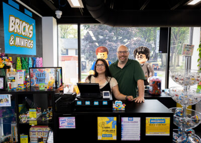 Image of the Bricks & Minifig owners Allison and Adam behind the front register