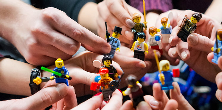 hands holding minifigs at party