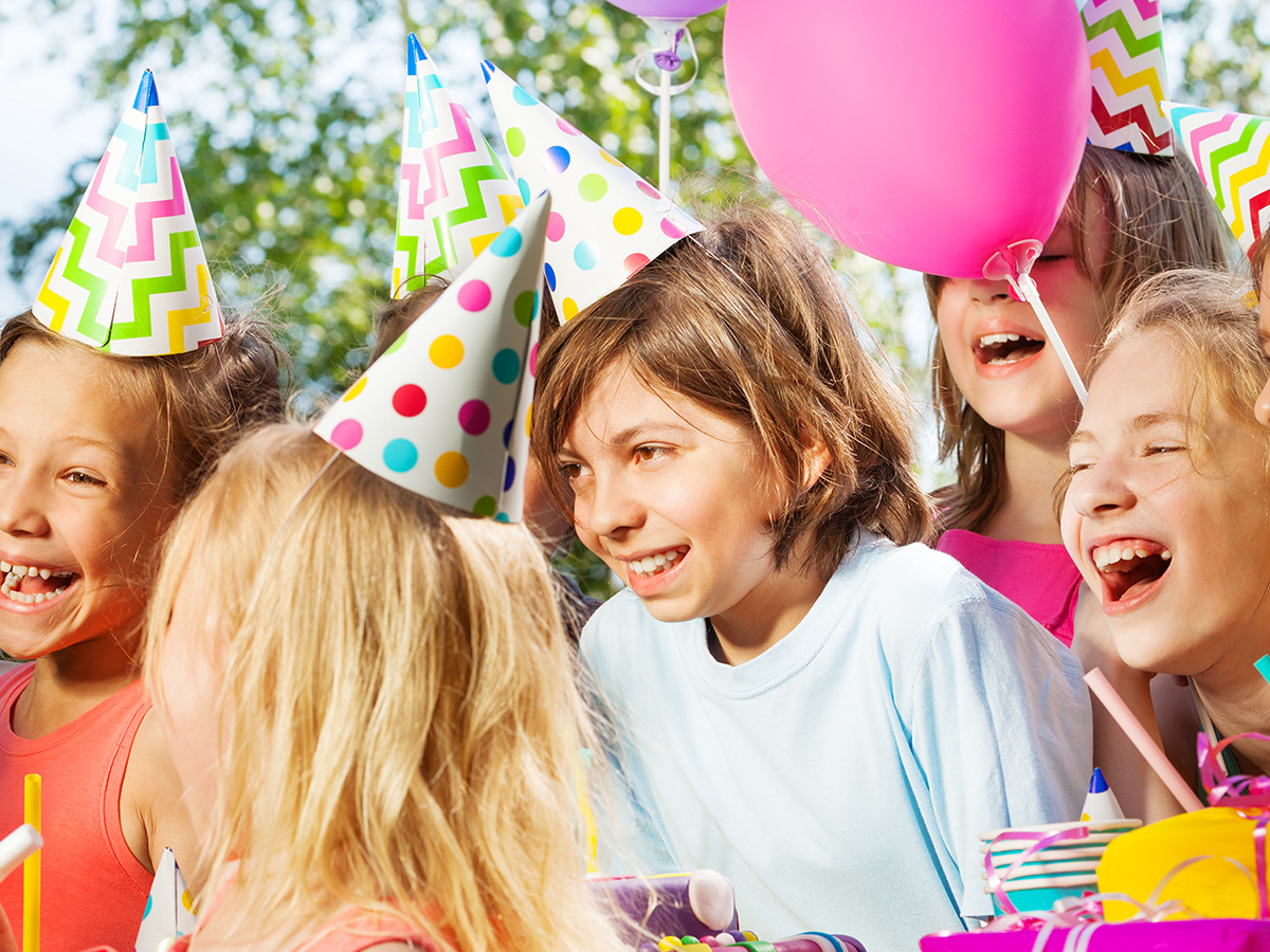 Children at a birthday party wearing party hats.