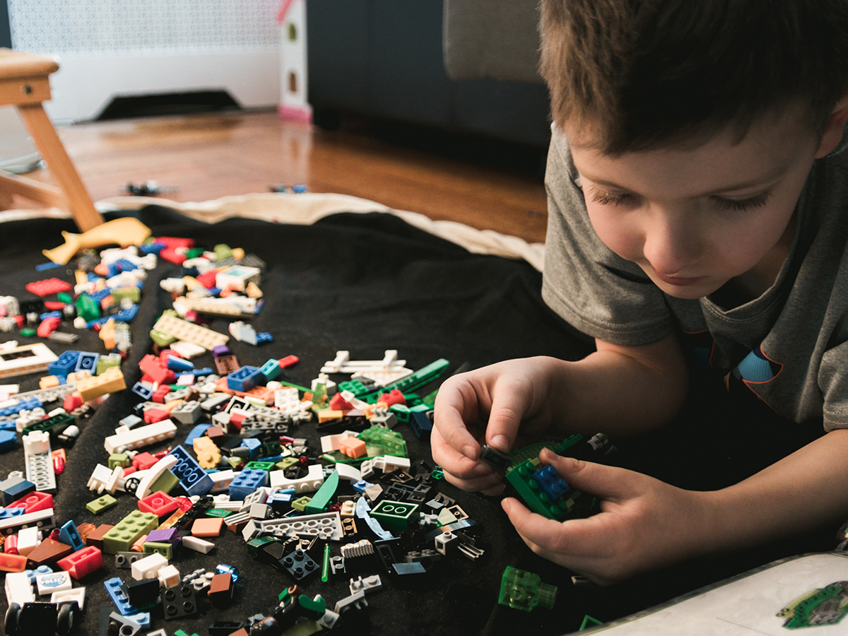 A kid laying on the ground building a LEGO® set.