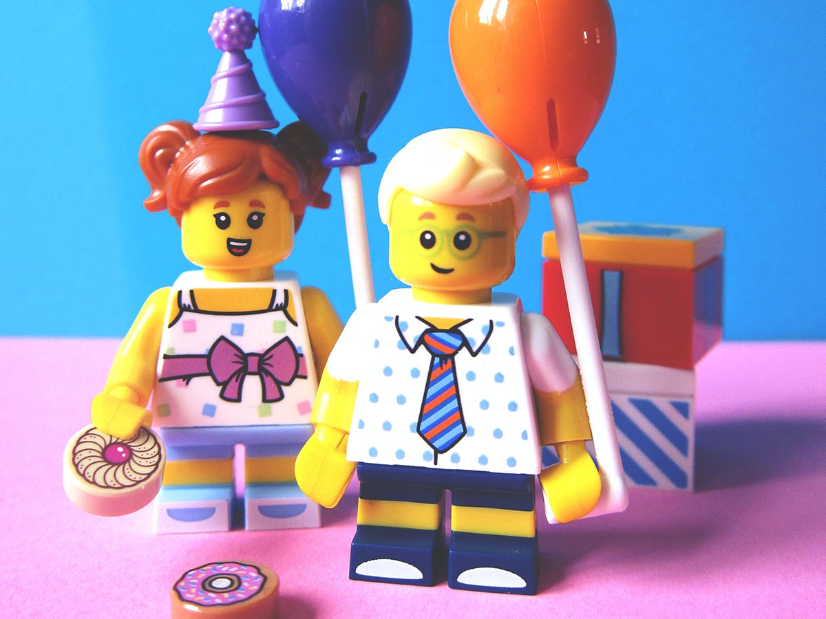 Girl and boy LEGO® minifigures holding balloons.
