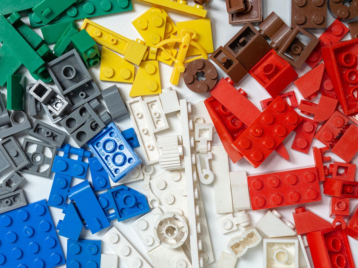 An assortment of various LEGO® pieces in brown, green, white, red, blue, and yellow.