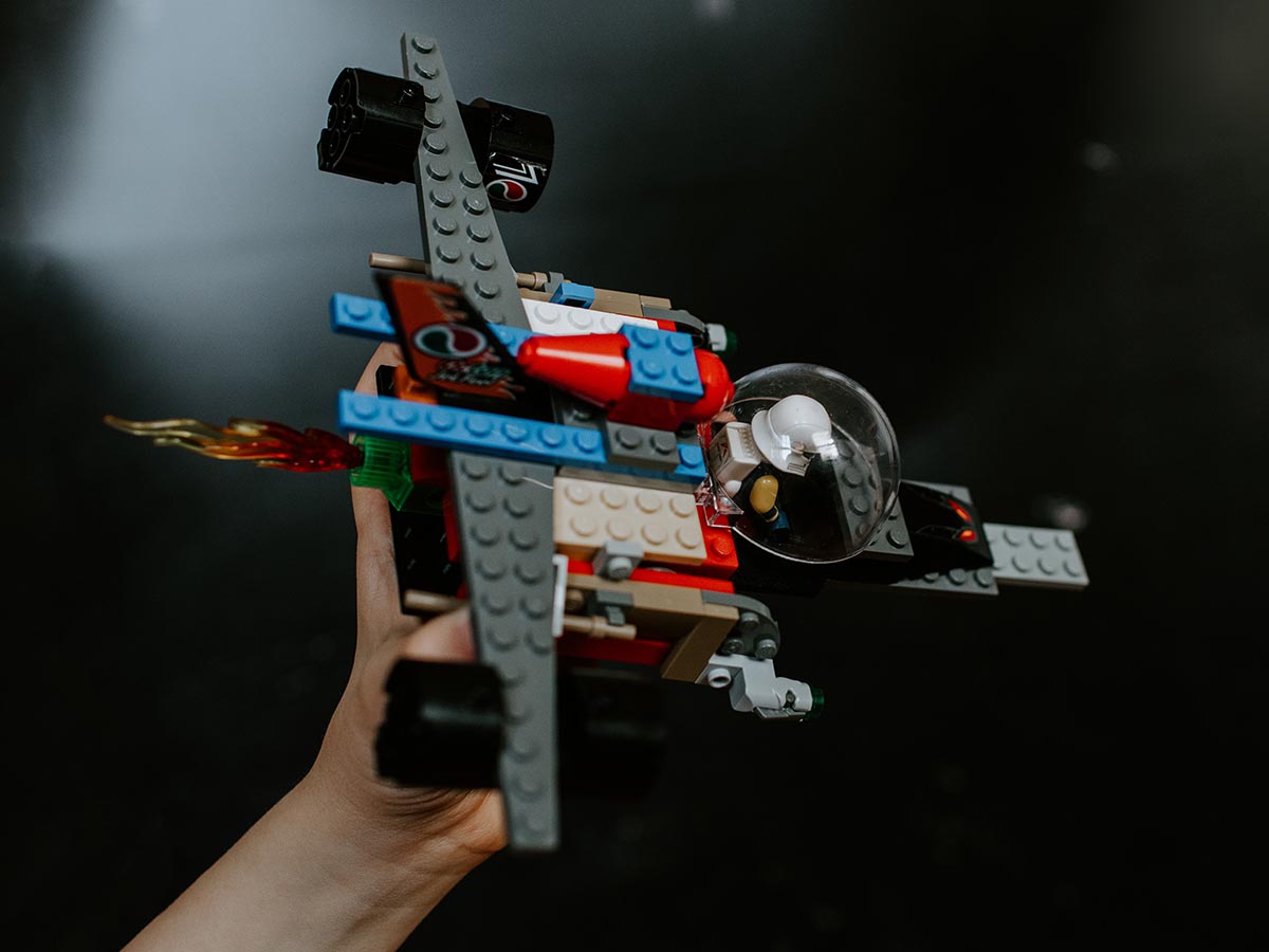 Kid flying a red and blue LEGO® jet plane.