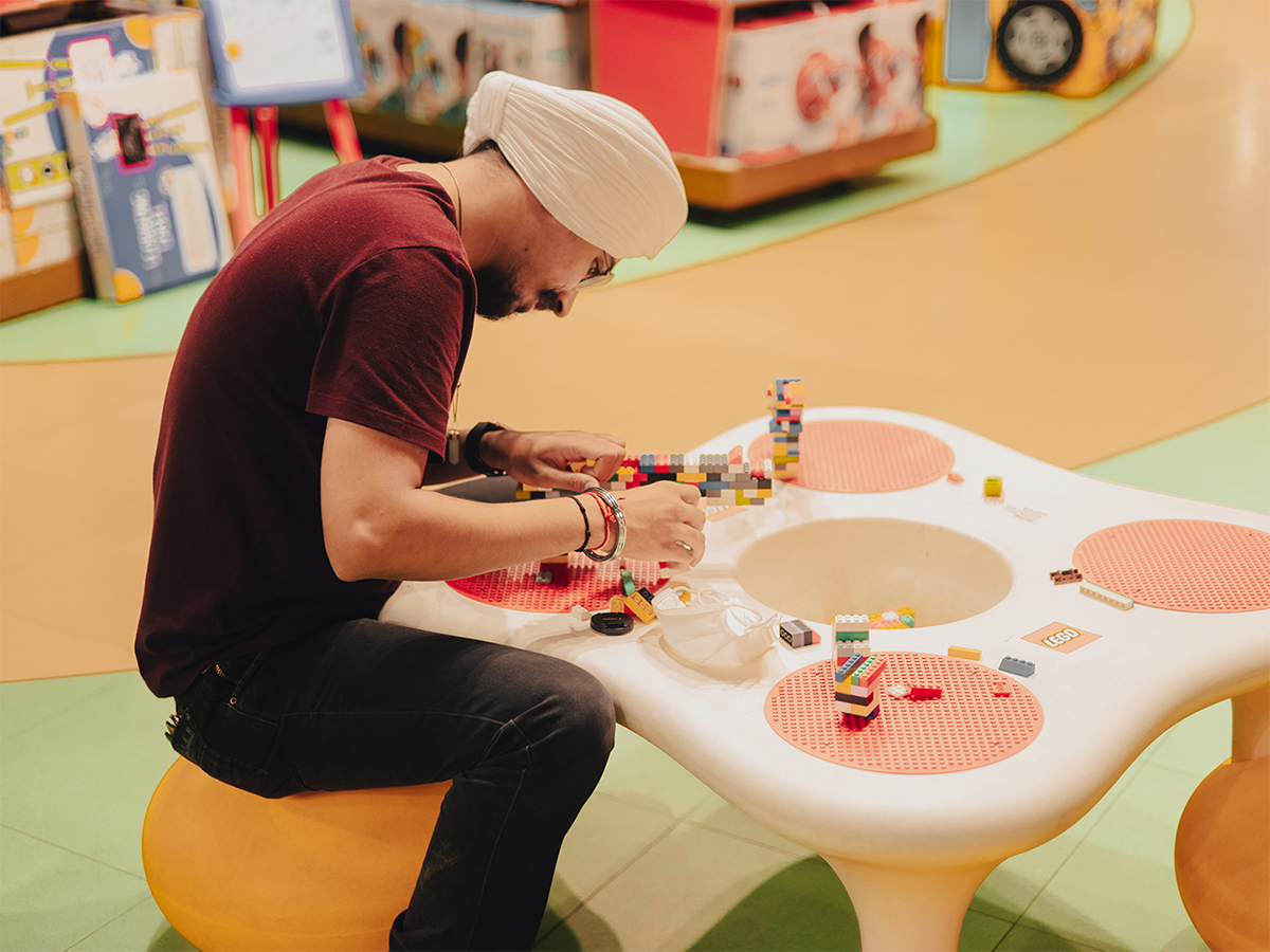 Man plays with LEGO® bricks on a round children’s table in a retail store.