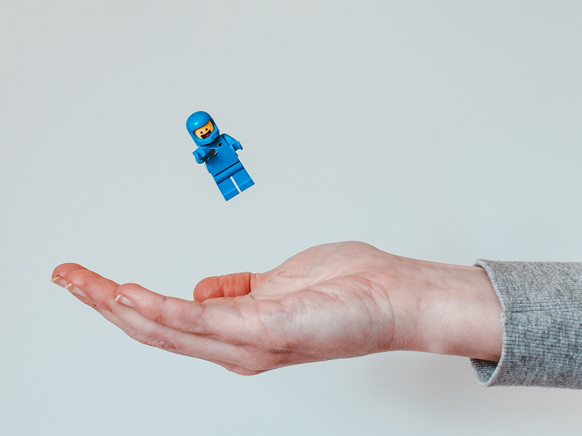 Blue LEGO® minifigure falling into a person’s hand.