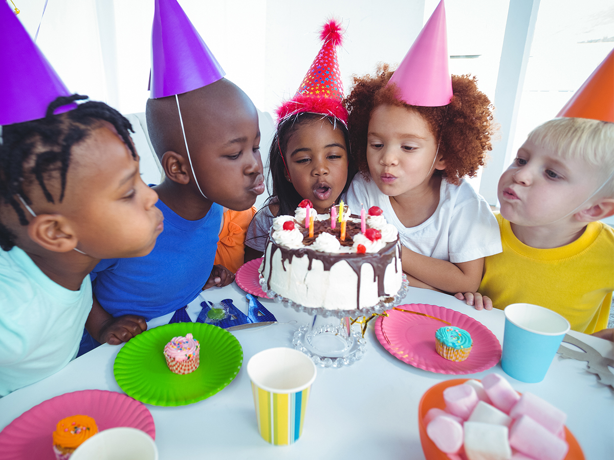 Children in party hats around a birthday cake