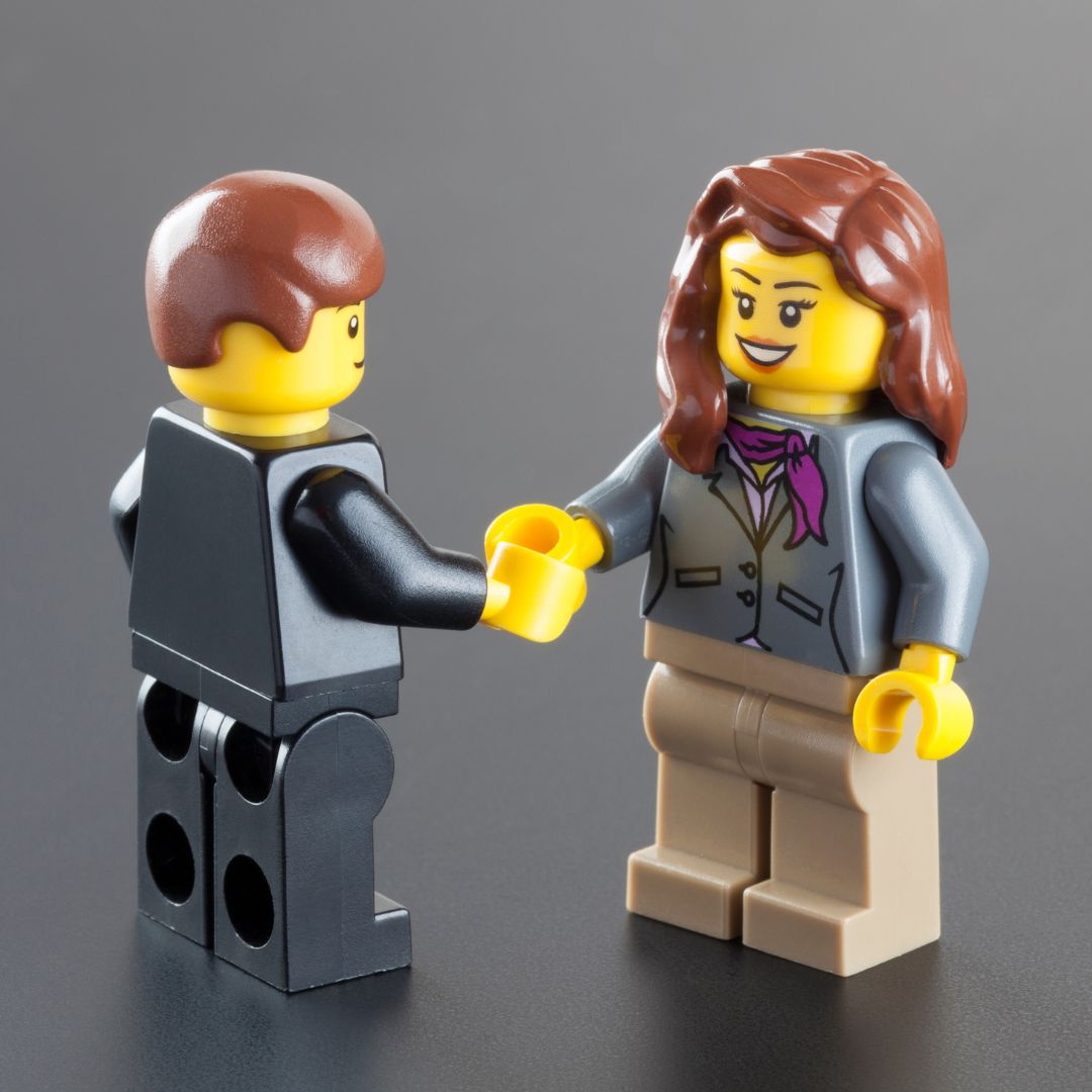 Business man and woman Lego figurines shaking hands