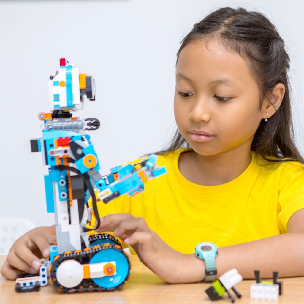 A girl playing with a robot built out of LEGO® bricks