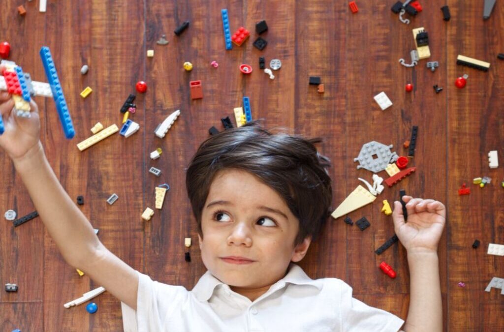 A child lying on the floor, surrounded by random LEGO® bricks.