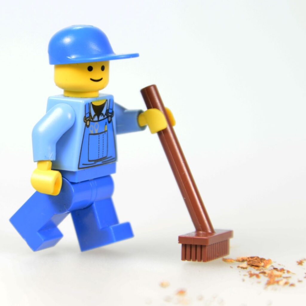 minifigure with broom sweeping up dirt