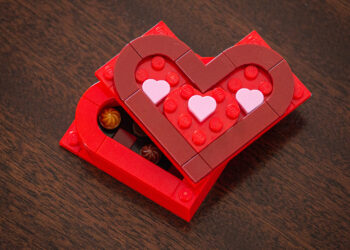 A Valentine's chocolate box build made with red and pink LEGO pieces. The lid is offset and with small chocolate pieces inside.