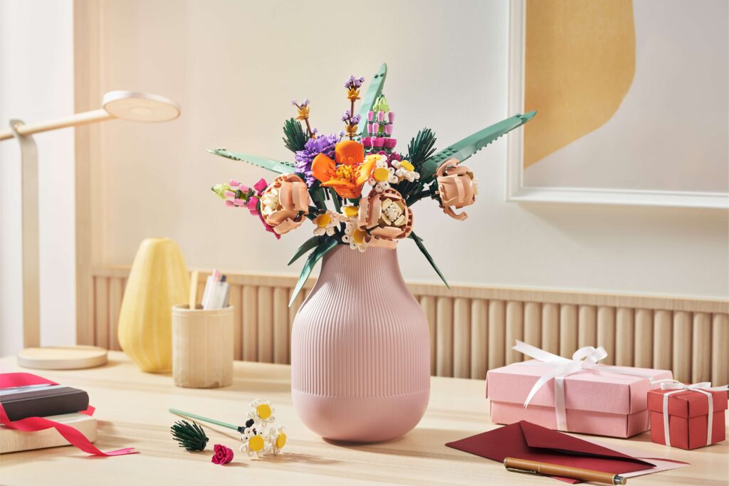 A bouquet of LEGO® flowers on a table surrounded by presents, stationary, and a couple more loose LEGO flowers.