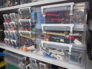 Plastic bins on a shelf filled with various disassembled LEGO® sets.