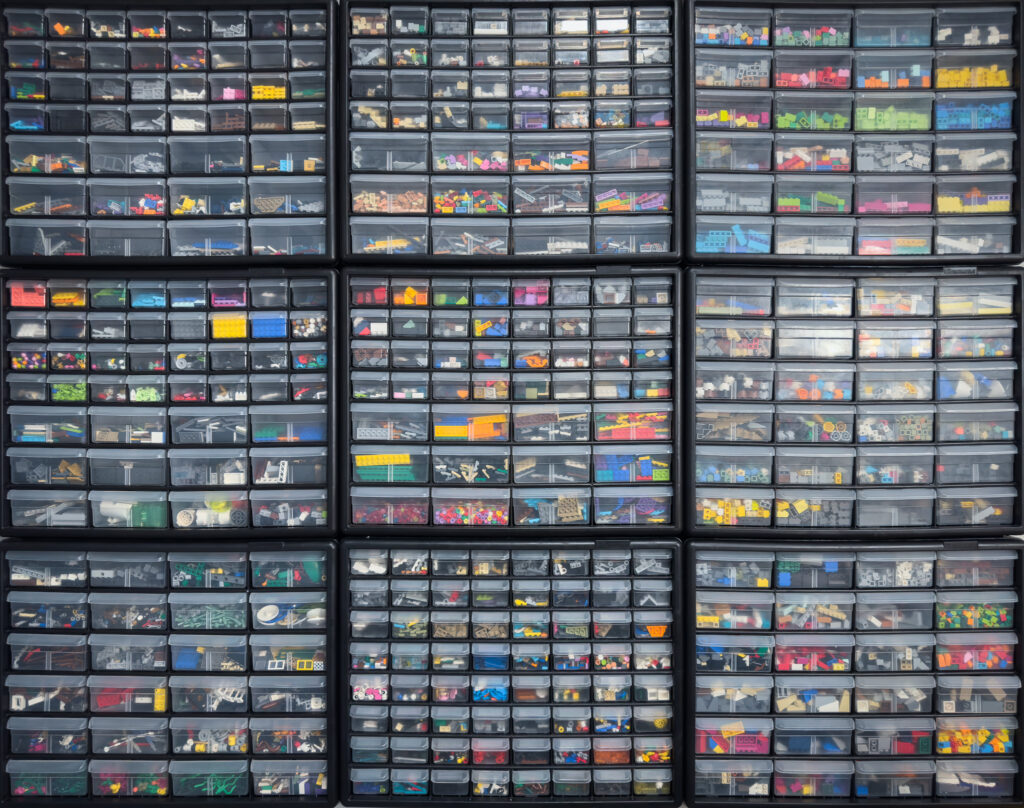 Sorted LEGO® pieces in plastic on containers on a shelf.