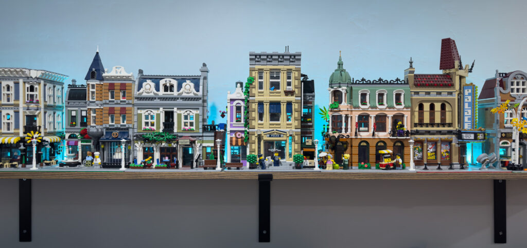 A LEGO® neighborhood of various buildings displayed on a wall shelf.