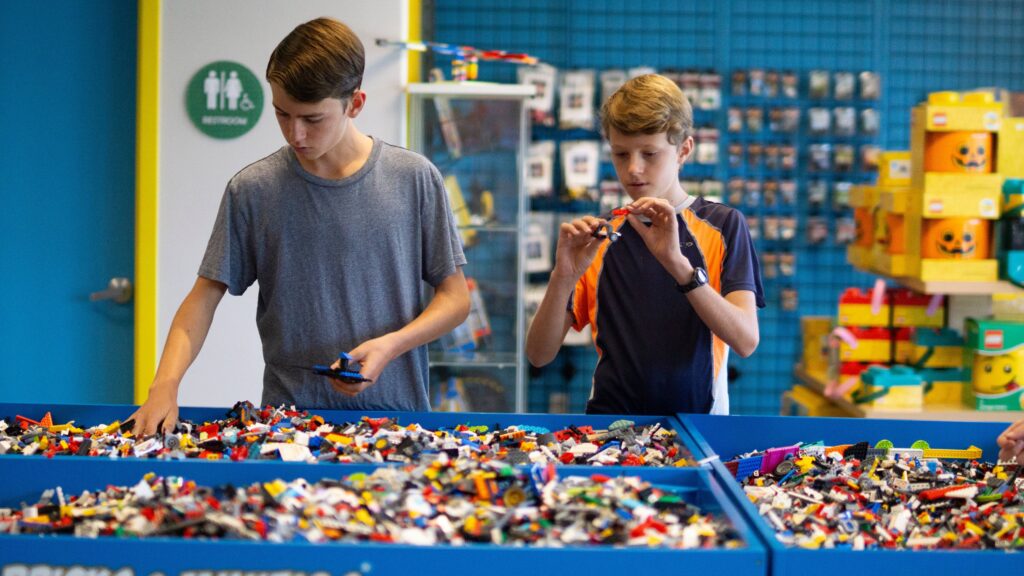 Two boys sorting through bins of bulk LEGO® pieces and building at Bricks  & Minifigs®