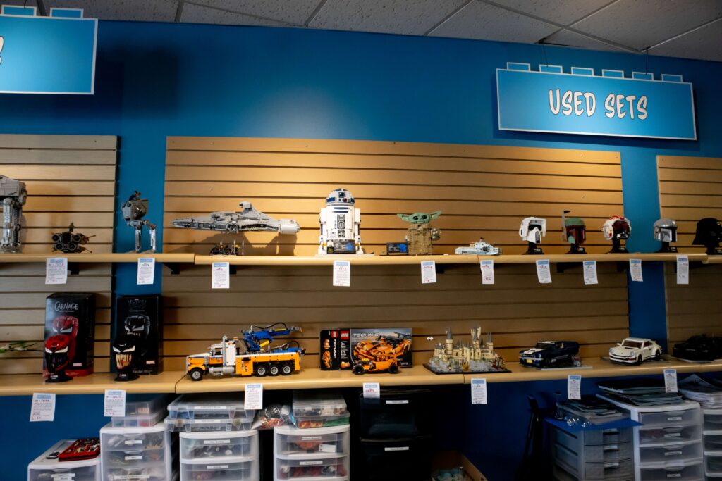 Various used LEGO® sets on the Used Sets shelf at a Bricks & Minifigs® store.